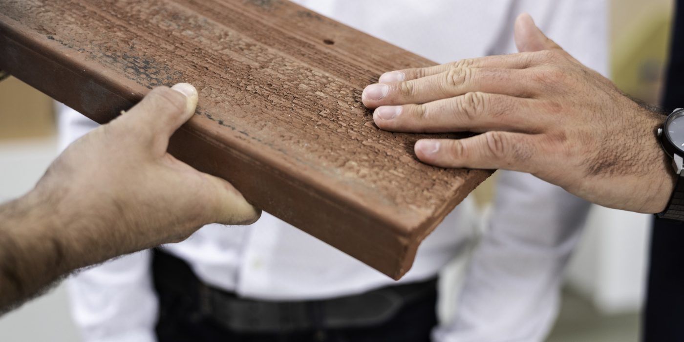 Hands touching surface structure of roof- and façade clay tile "Urban"